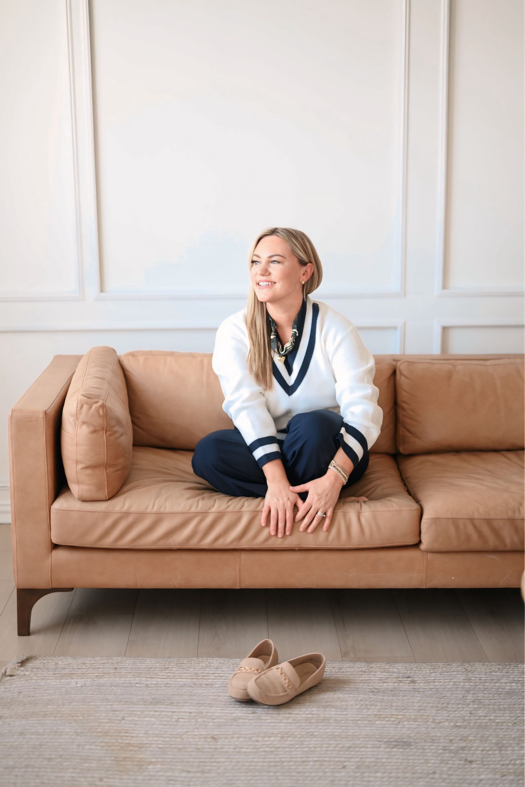 Audrie Dollins on leather couch in navy and white sweater.