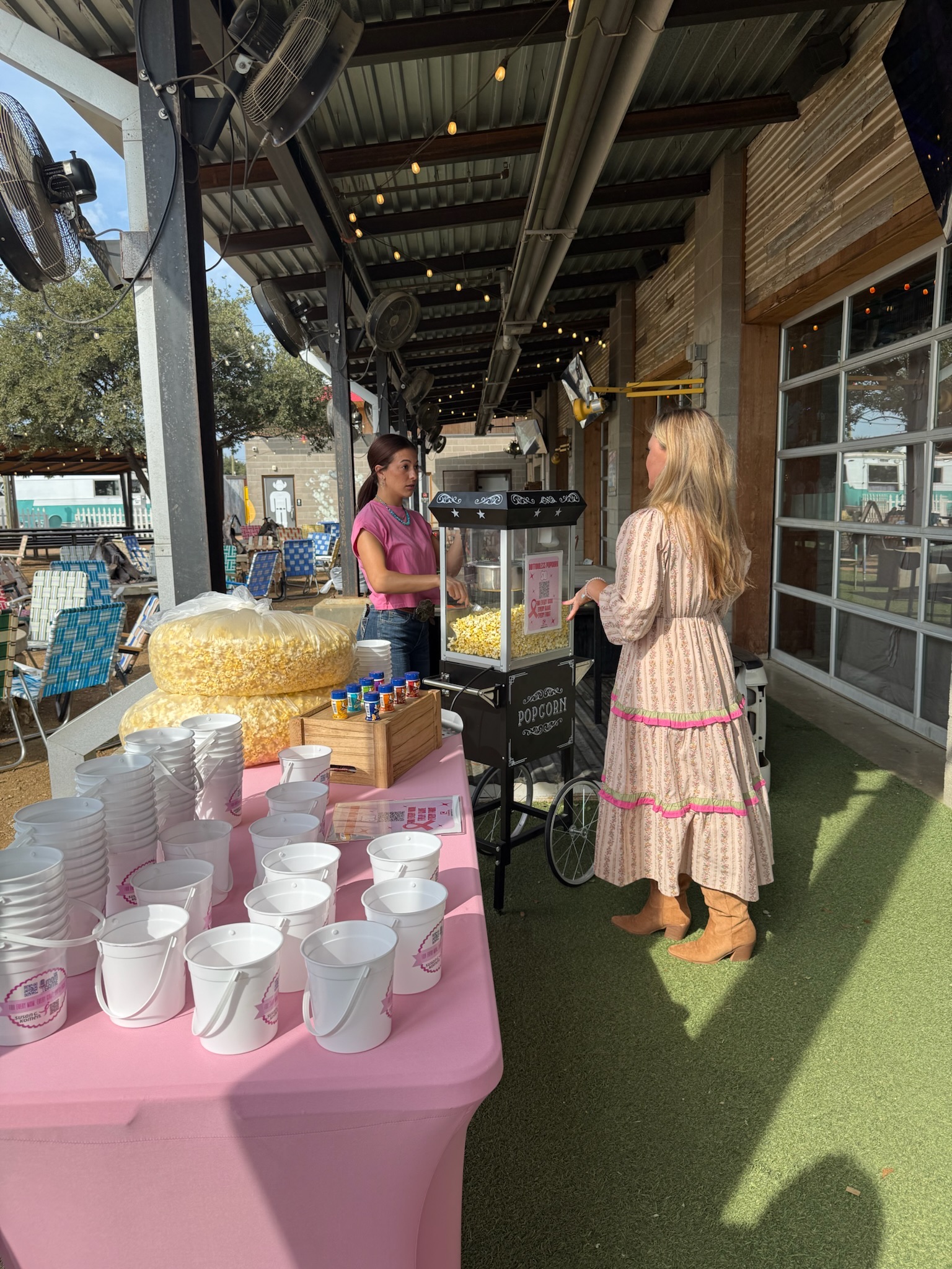 Audrie Dollins standing at the custom popcorn stand at The Mom Game Live event at Truck Yard Fort Worth supporting Susan G. Komen for breast cancer awareness.