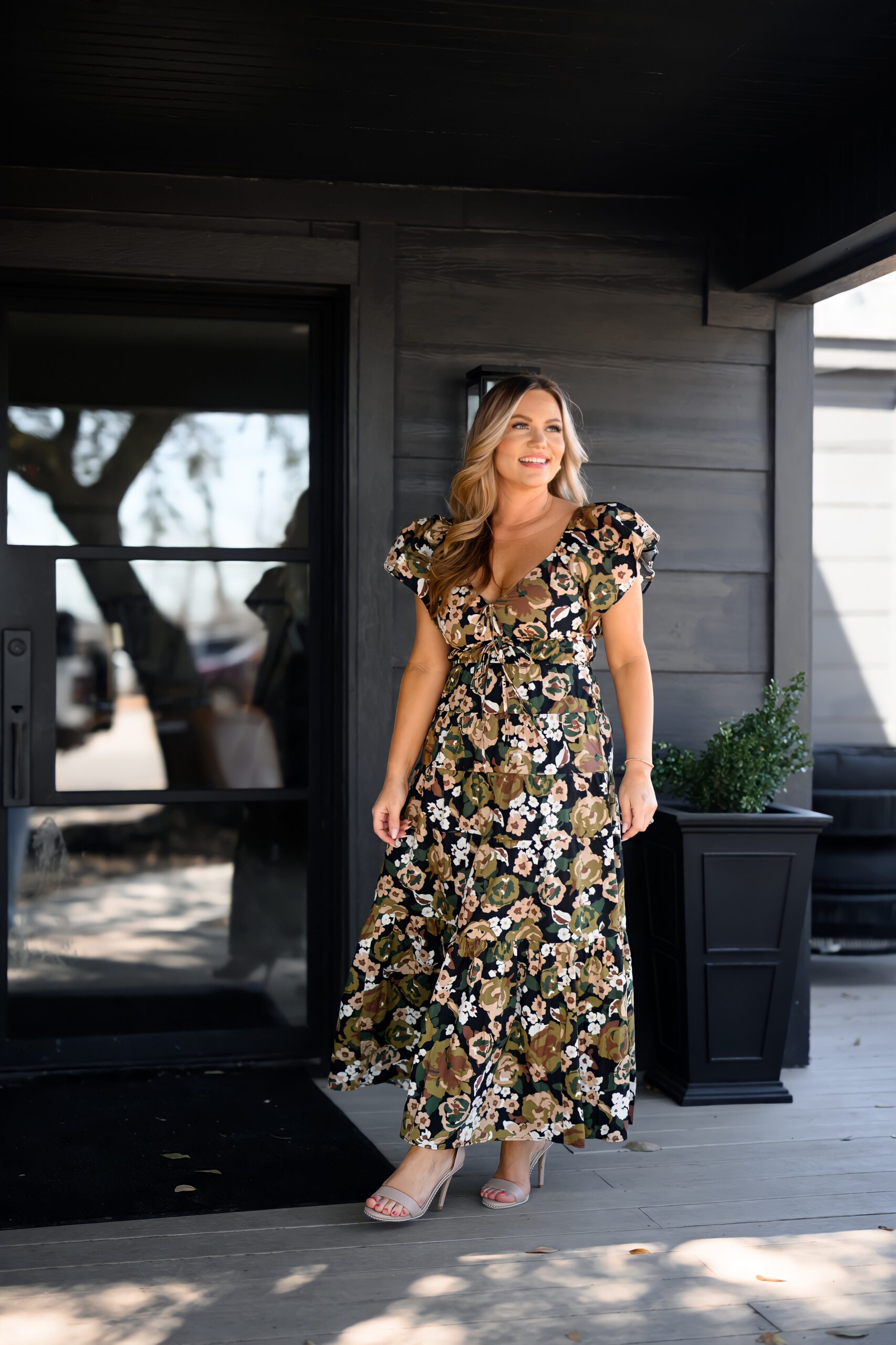 Audrie Dollins smiling outdoors in a long floral dress during a lifestyle photoshoot for her blog, sharing inspiration and entrepreneurial insights.