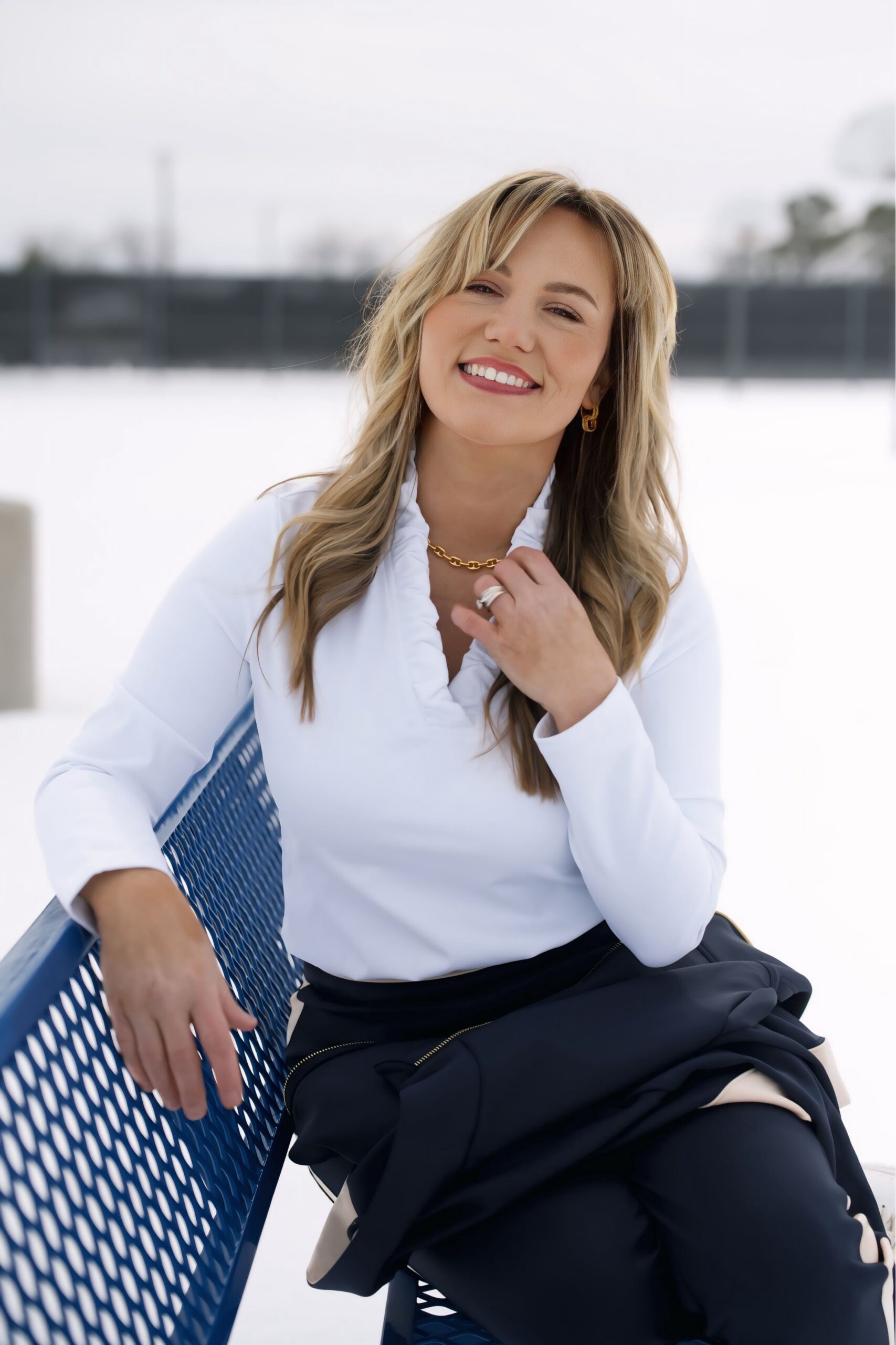 Audrie Dollins, digital marketing strategist seated outdoors in a snowy setting, wearing a white blouse and gold jewelry, featured in a blog discussing Facebook as a high converting platform driven by buyer intent, clicks, and revenue focused performance.