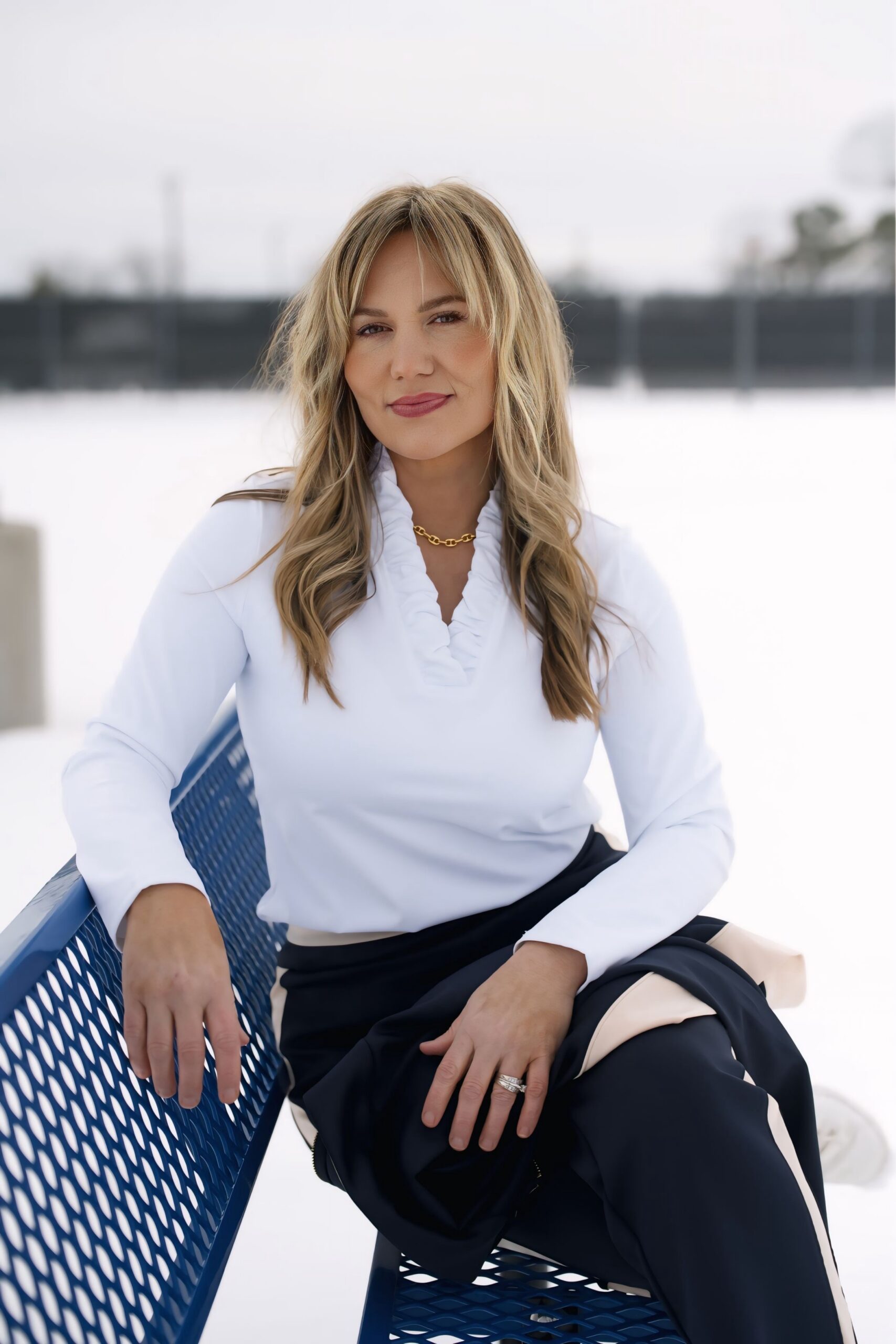 Audrie Dollins seated outdoors in a snowy setting, wearing a white blouse and gold necklace, looking forward with a confident expression, featured in a blog about Facebook conversion strategy, buyer intent, and revenue driven performance.