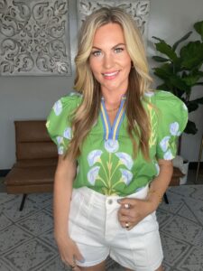 Audrie Dollins Founder & CEO of Parlay Collective wearing green blouse and white shorts .