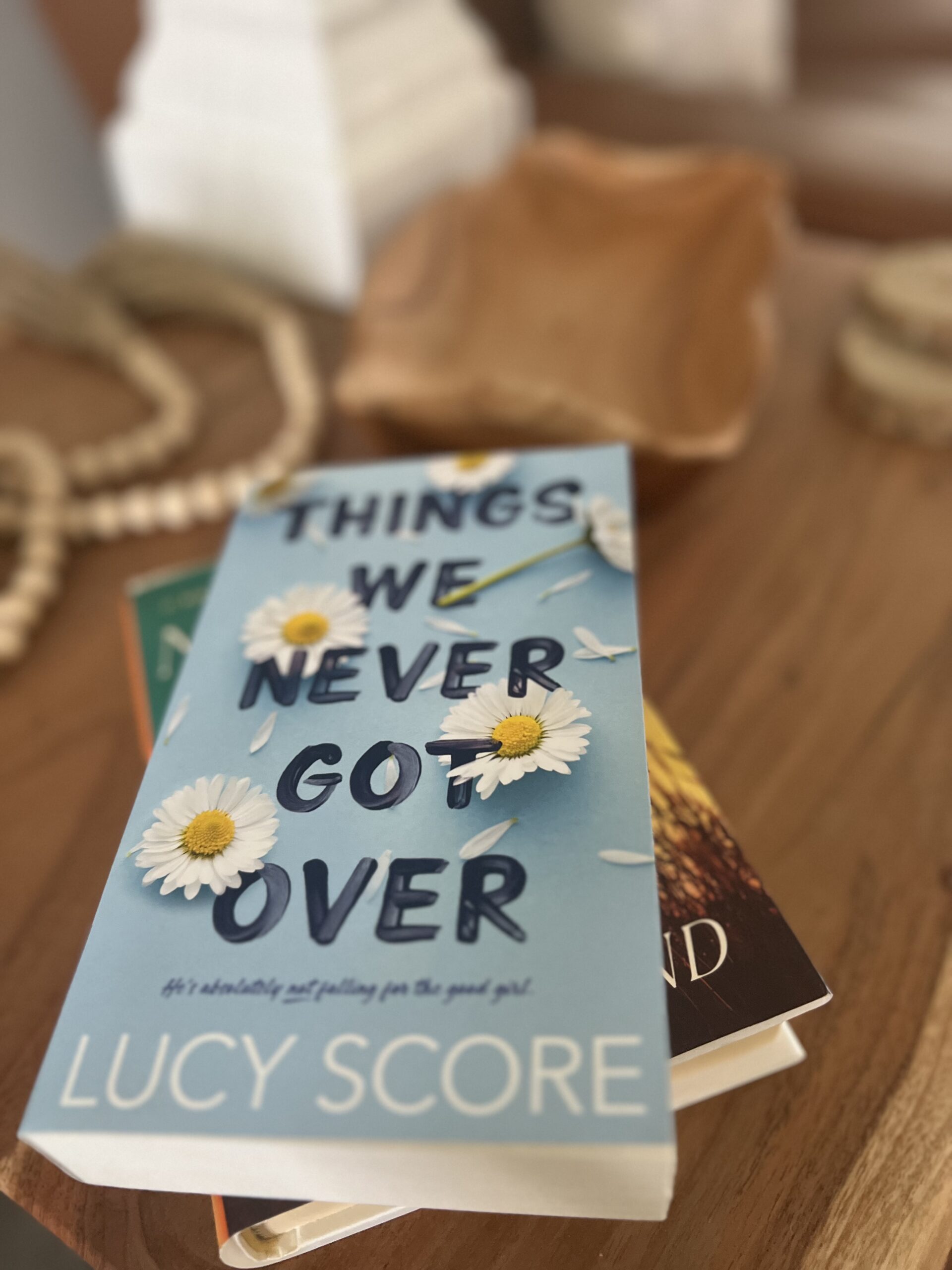 Lucy Score's "Things We Never Got Over" styled on a coffee table with layered books and neutral decor, highlighting a popular romance novel and must-read contemporary fiction recommendation.
