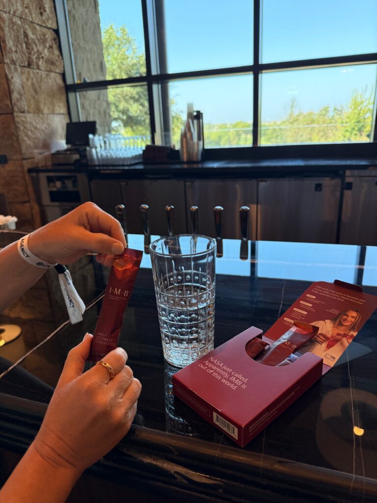 IM8 Daily Ultimate Essentials supplement being prepared in a glass at LTKCon 2026, highlighting a wellness brand partnership with Parlay Collective and its influencer gifting program.