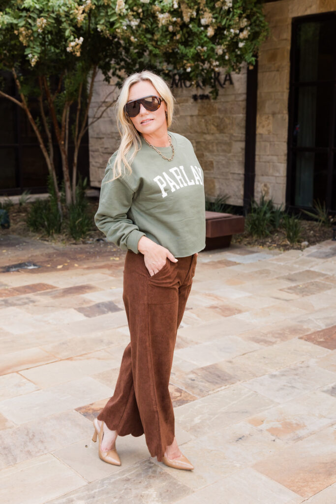 Audrie Dollins wearing a green Parlay Collective sweatshirt at PGA Frisco during LTKCon 2026, representing her Texas-based influencer management agency and entrepreneurial leadership in the creator economy.